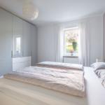 Schlafzimmer mit Doppelbett, Kleiderschrank und Fenster mit Blick auf Garten.
