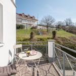 Terrasse mit Tisch und Stühlen. Blick auf Garten und Spielplatz.