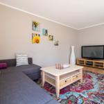 Wohnzimmer mit Sofa, Couchtisch und Fernseher auf Holzregal.