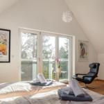 Schlafzimmer mit Balkon, Kunstwerken und Bett mit Handtüchern.