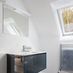 Badezimmer mit Waschbecken, Spiegel und Dachfenster. Handtuchhalter und gefaltete Handtücher.