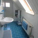 Badezimmer mit Dusche, Waschbecken und blauen Fliesen unter Dachschrägen
