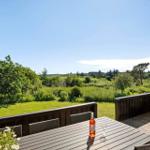 Terrasse mit Tisch, Stühlen und Weinkrug. Blick auf grünes Gelände und Bäume.