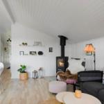 Wohnraum mit Sofa, Kamin und Holzboden. Weiße Wände und Decke.