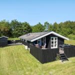 Schwarzes Holzhaus mit Terrasse und Garten. Umgeben von Wald und Gras.
