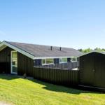 Ein dunkel verkleidetes Haus mit Garage und Schuppen auf grünem Grund.