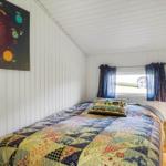 Schlafzimmer mit Bett, Patchwork-Bettwäsche und Sonnensystem-Bild an der Wand.