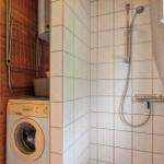 Dusche mit Duschbrause, Waschmaschine und Holzwand im Badezimmer.