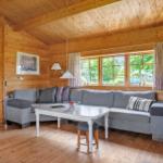 Wohnzimmer mit Holzwand, Sofa, Tisch und Fenster mit Blick auf Grün.