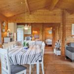 Ein Esszimmer mit Tisch und Stühlen, Küche und Wohnbereich in einem Holzhaus.