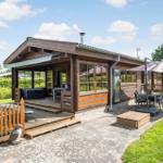 Holzhaus mit Terrasse, Grill und Sitzgelegenheiten im Garten.