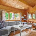 Wohnzimmer mit Holzwand, Sofa, Tisch und Kaminofen.