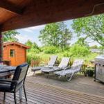 Terrasse mit Grill, Liegestühlen und Tisch unter Holzüberdachung. Blick auf grüne Landschaft.