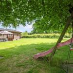 Hinterhof mit Spielplatz, Rutsche und Sitzgelegenheit unter Bäumen.