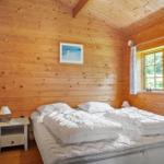 Schlafzimmer mit Holzwand, Bett und Fenster. Neben dem Bett steht ein Nachttisch.
