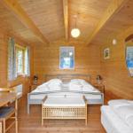 Schlafzimmer mit Holzwand, Bett, Schreibtisch und Fenster.