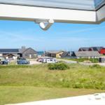 Blick vom Fenster auf einen Parkplatz mit Autos und Häusern am Meer.