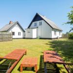 Zwei Häuser mit Garten, Sonnenliegen und Bäumen. Hinterhof mit Holzgeländer.