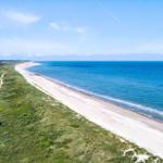 Strand mit Dünen, kleines Haus und Wanderweg an der Küste