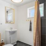 Badezimmer mit Waschbecken, Spiegel, Dusche und Fenster