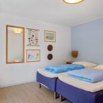 Zwei Betten mit blauen Decken, Wandbilder und Spiegel in einem Raum mit Holzboden und blauer Wand.