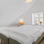 Schlafzimmer mit Dachschrägen, Bett, Fenster und Nachttischen mit Lampen.
