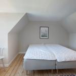 Schlafzimmer mit Dachschrägen, Bett, Stuhl und Fenster.