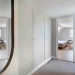 Flur mit Kleiderschrank und Blick in zwei Schlafzimmer mit Holzboden und Fenstern.