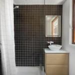 Bad mit Dusche, Waschbecken und Fenster mit Blick auf die Landschaft.