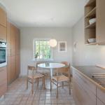 Küche mit Essbereich, Holzmöbel und Fenster zum Garten.