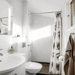 Badezimmer mit Dusche, Waschbecken und Toilette. Duschvorhang und Handtuch hängen an der Wand.