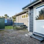 Haus mit Terrasse, Tisch, Bank und Gartenhütte. Eingangstür mit Glasfenster.