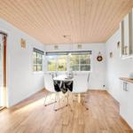 Esszimmer mit Holzdecke, Tisch, Stühle und Fenster. Küche mit Arbeitsplatte und Schränken.