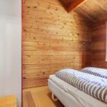 Schlafzimmer mit Holzwand, Bett und Fenster.