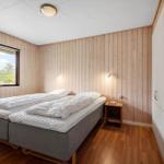 Schlafzimmer mit Doppelbett, Holzwand und Fensterblick auf Außenbereich.