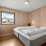 Schlafzimmer mit Holzwand, Bett und Fensterblick auf Haus.
