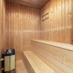 Sauna mit Holzwand und Sitzbank, Heizgerät an der Wand.