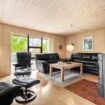 Wohnzimmer mit Holzwänden, schwarzen Ledermöbeln und Kaminofen.