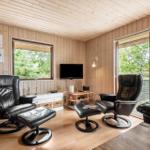 Wohnzimmer mit zwei schwarzen Sesseln, Fernseher und Holzwandverkleidung.