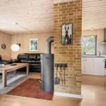 Wohnzimmer mit Sofa, Kamin und Küche im Hintergrund.