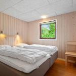 Schlafzimmer mit Doppelbett, Holzwandverkleidung und Fenster mit Blick auf Bäume.