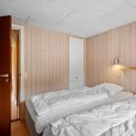 Schlafzimmer mit Holzwand, Bett und Schrank. Tür führt in einen Flur.