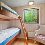 Zimmer mit Doppelstockbett, Fenster mit Waldblick und Stuhl.