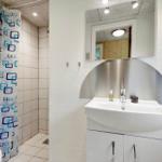 Badezimmer mit Dusche, Waschbecken und Spiegel.