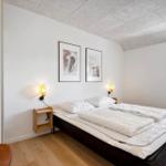 Schlafzimmer mit Doppelbett, zwei Wandlampen und zwei Bildern an der Wand.