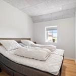 Schlafzimmer mit Bett, Fenster und Holzboden.