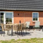 Terrasse mit Tisch, Stühlen und Liegen vor einem Backsteinhaus mit Dach.