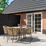 Terrasse mit Tisch, Stühlen und Schaukel vor einem Backsteinhaus mit Glastür.