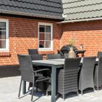 Terrasse mit Tisch, Stühlen und Grill vor rotem Backsteinhaus.
