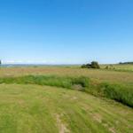Weitläufiger Grasbereich mit Blick auf Golfplatz und Wasser unter blauem Himmel.